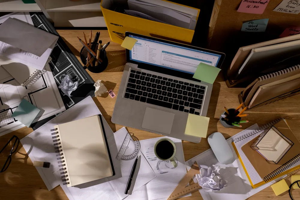 Cluttered founder desk with laptop, post-it notes and coffee; visual of ADHD productivity coaching for executives in London