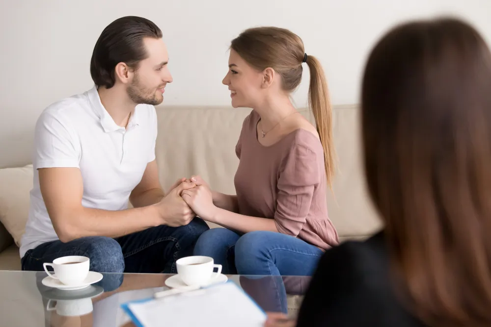 A couple holding hands and talking together during a couples therapy session.
