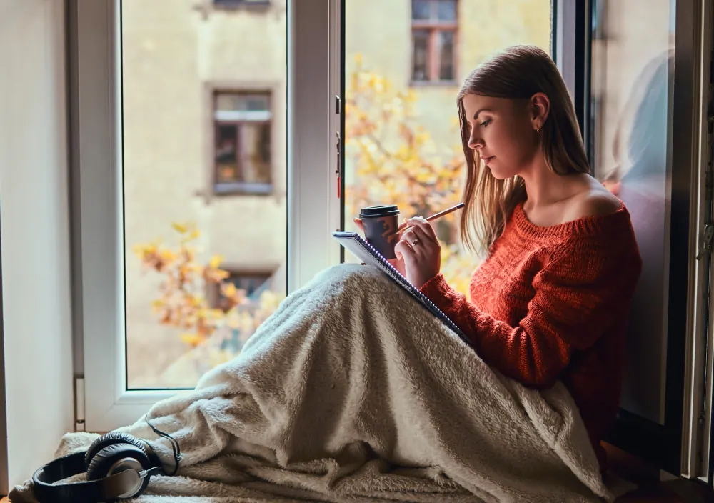 Person calmly writing a thought record in a notebook by a bright window while practising cognitive reframing for anxiety