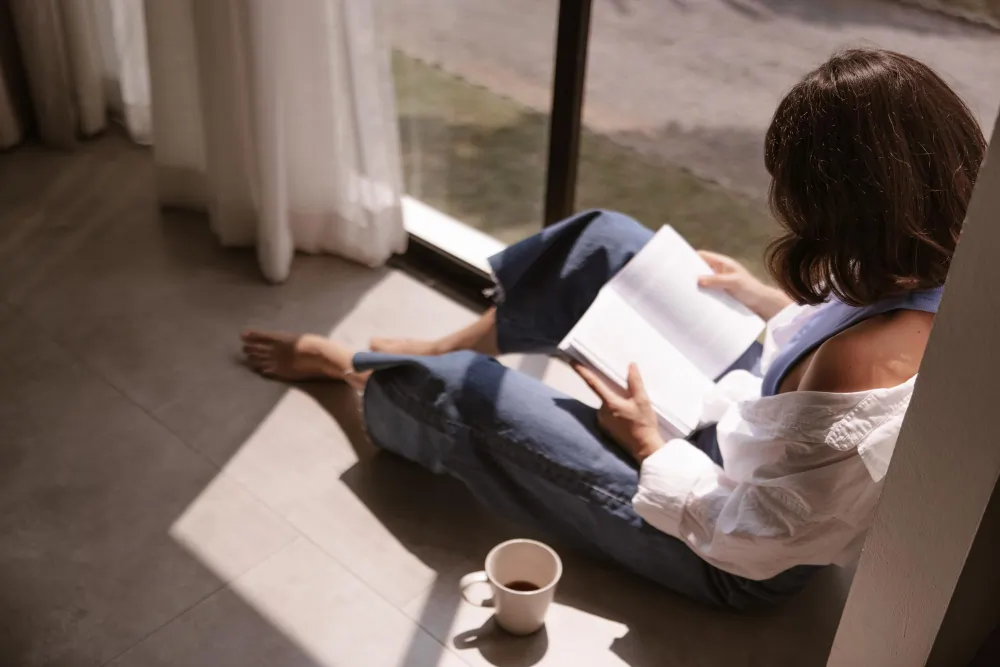 A woman reading calmly in soft natural light, considering DBT therapy options in London