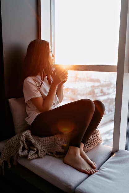 Woman sitting calmly by a sunlit window with a warm drink, reflecting the calm that OCD therapy in London can bring